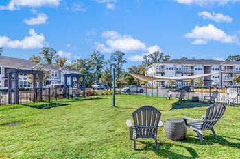 Two chairs and a table are on a lawn in front of a building.